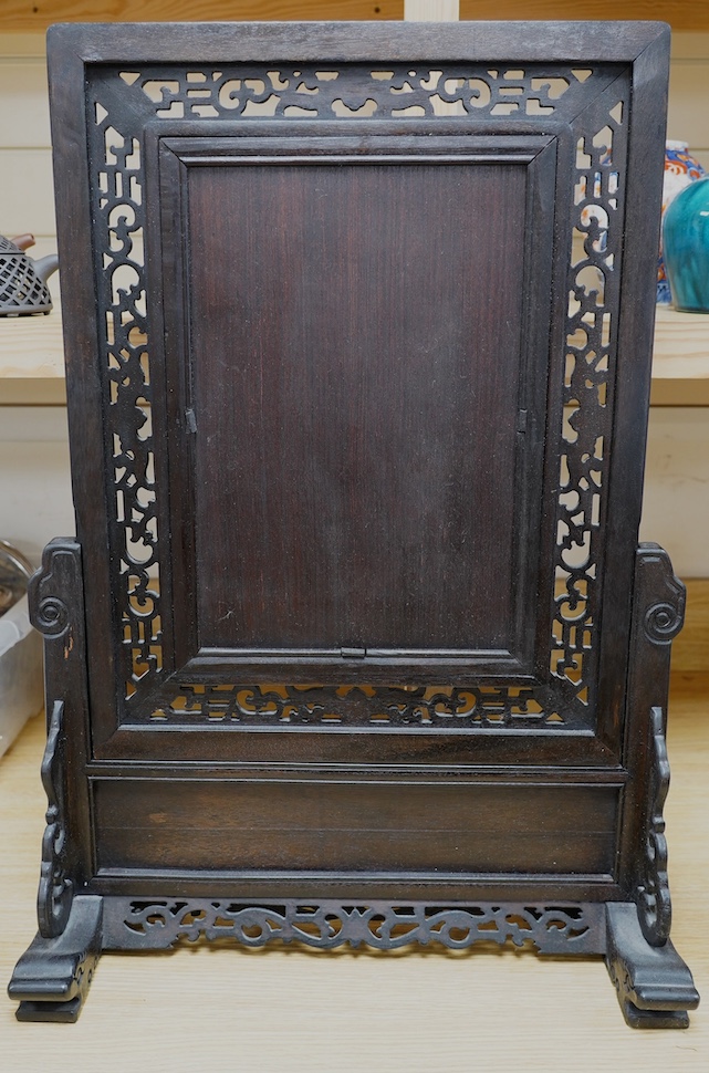 A Chinese carved table screen with a famille rose central plaque, screen 66cm high, plaque 35cm high. Condition - good